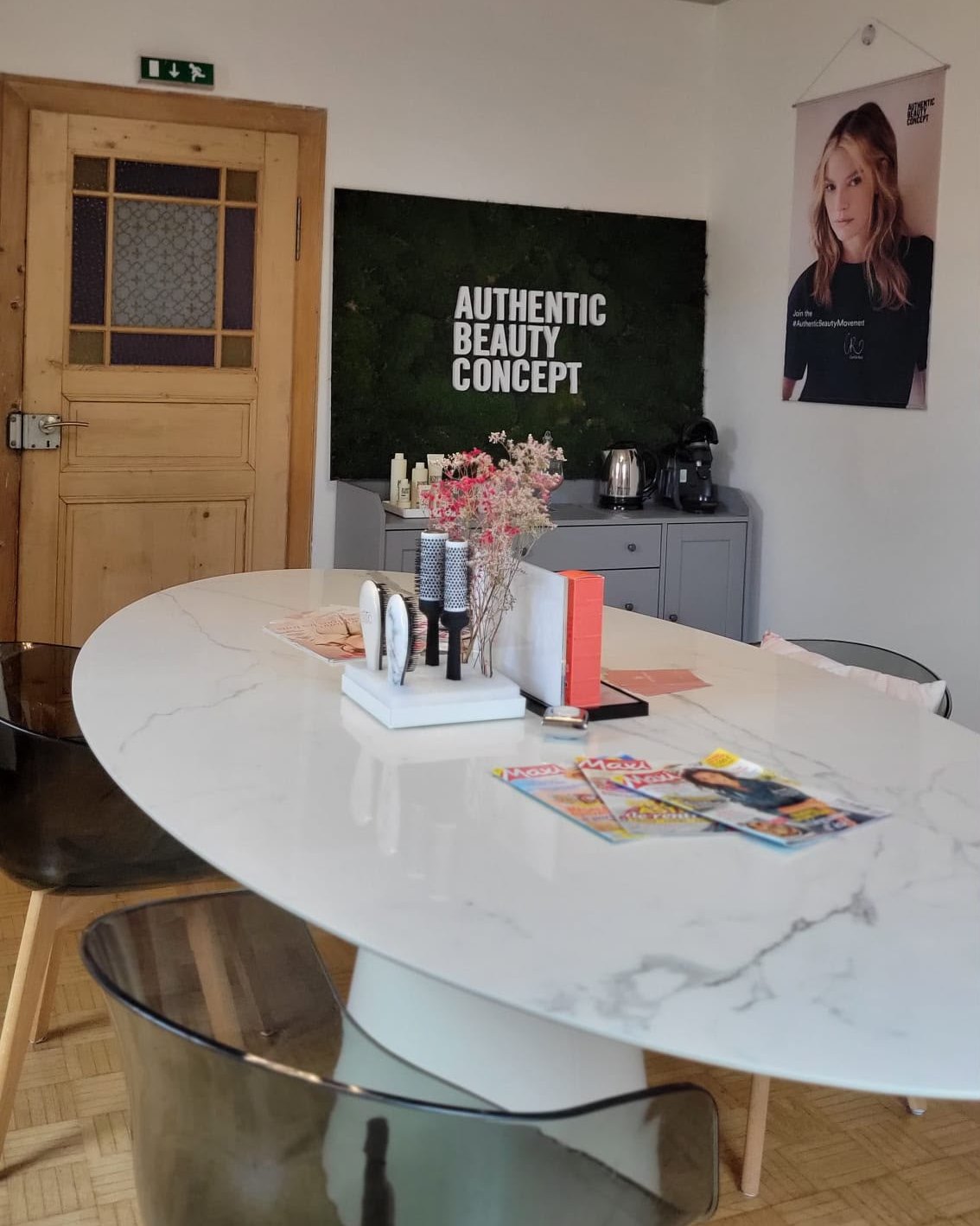 L'accueil du salon : table ovale en marbre, suspensions annulaires et mur végétal